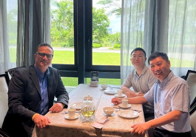 Three people sitting at a table eating and smiling at the camera