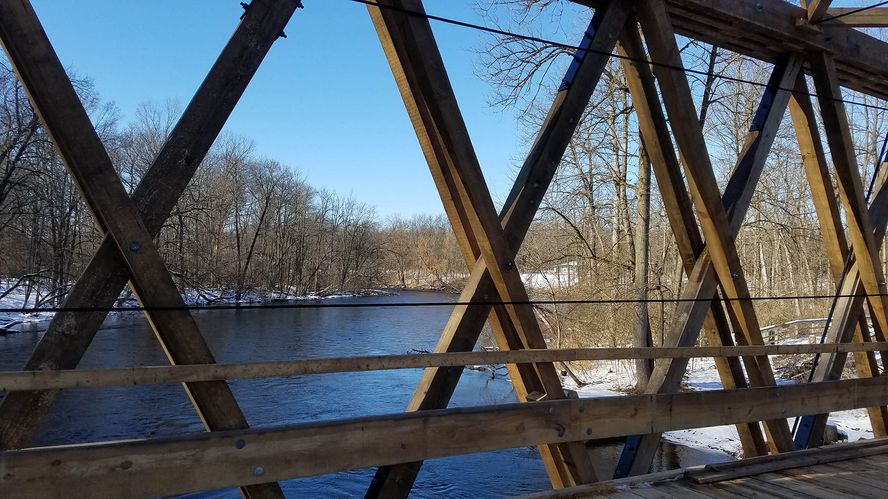 view out to the lake through the criss crossed planks on the bridge