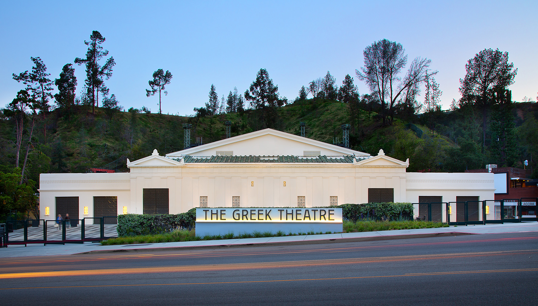 white marble building with dark brown doors with trees behind it