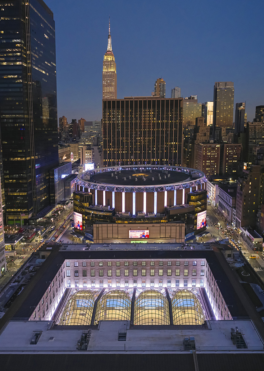 aerial view of a new train station showing the glass topped domes, illuminated buildings, and road traffic