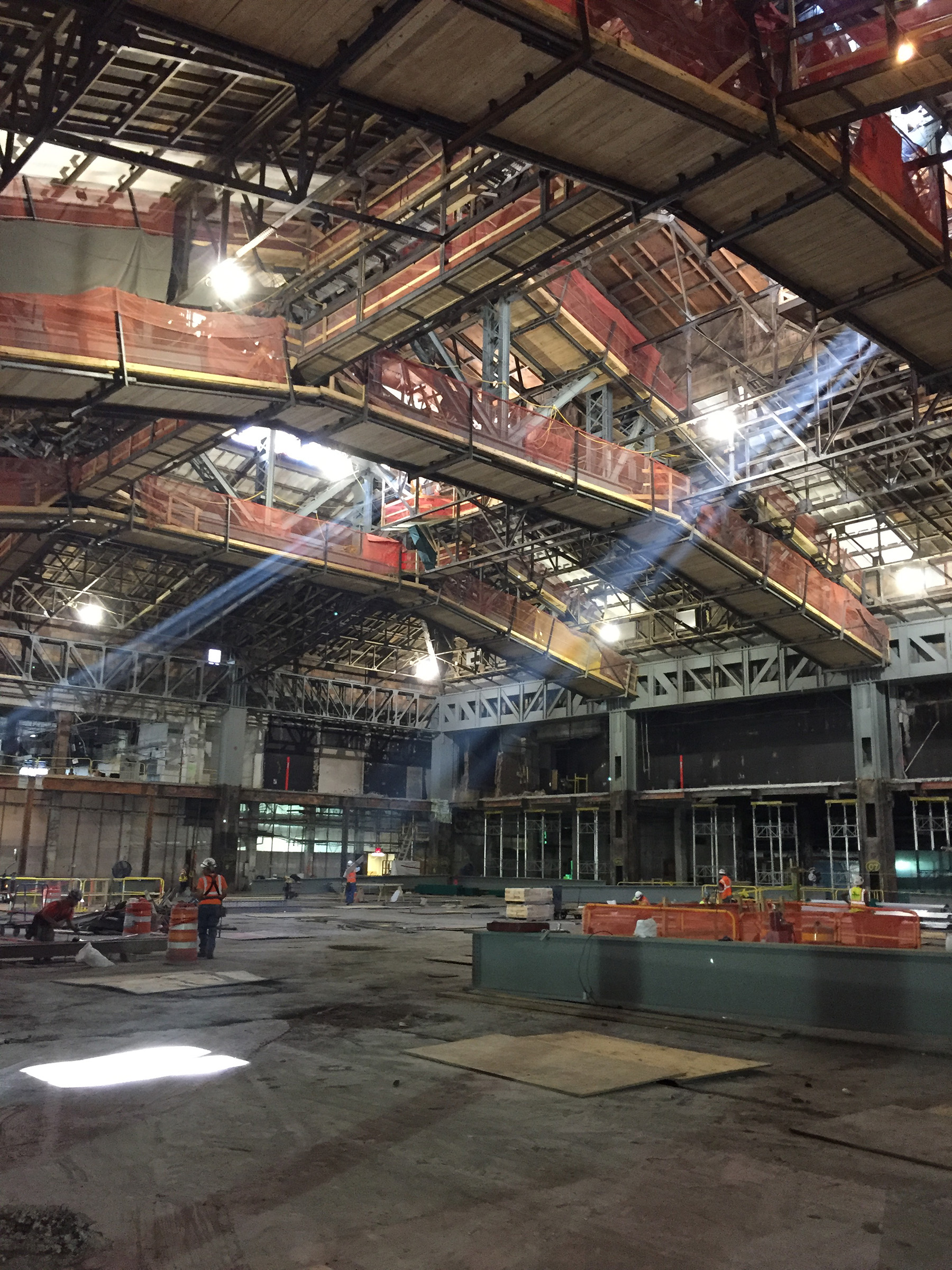 in construction photo of a train hall that has 20 foot ceilings. The glass top allows light to stream in.