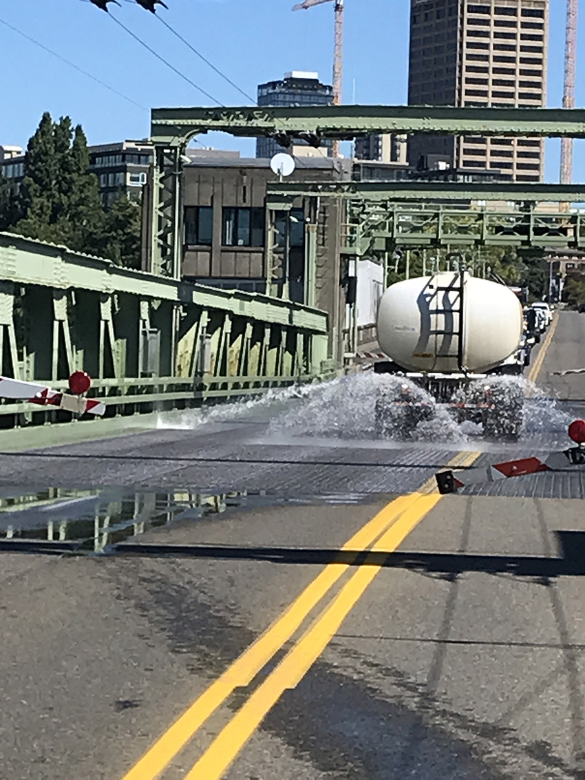 Truck driving down a street spraying water on the pavement