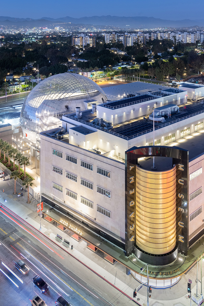  Several buildings lit up at night showing the academy museum of motion pictures in Los Angeles