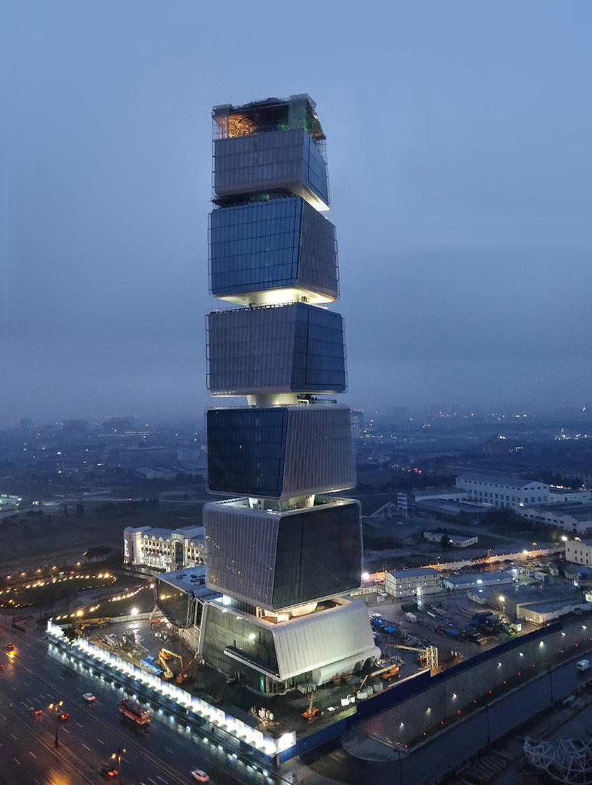 Photo shows a building composed of stacked cubes suspended from a central concrete core. 