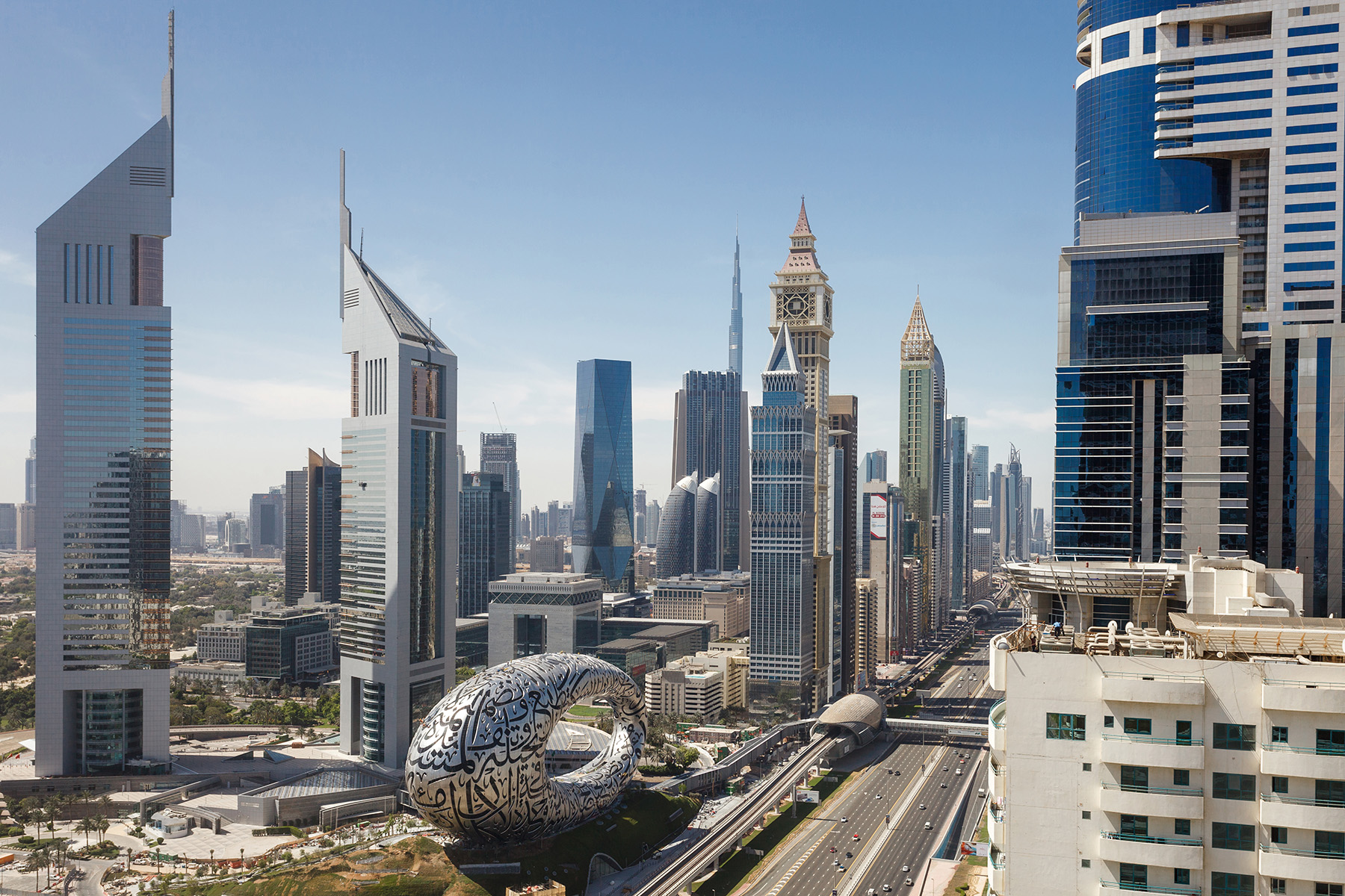 Image shows circular structure surrounded by mass transit and skyscrapers. 