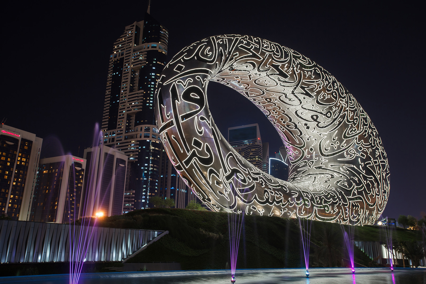 A round structure with a hole in the middle is shown with an illuminated facade.