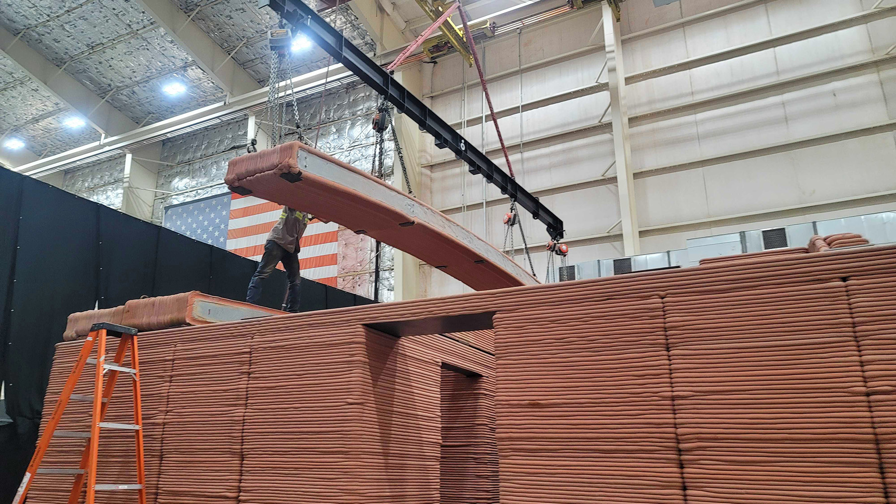 Work crews install a roof panel on top of a structure.