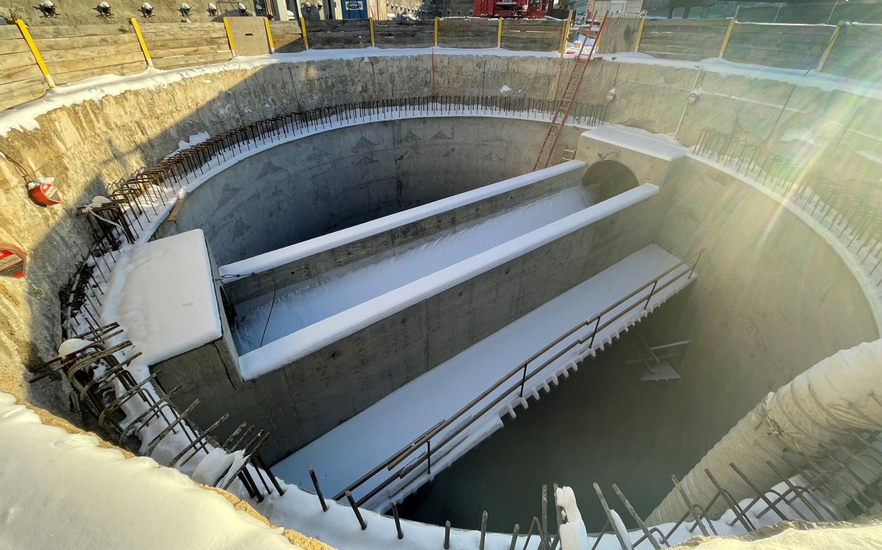 A two-sided weir is shown in the photo. It sits within a circular concrete structure.