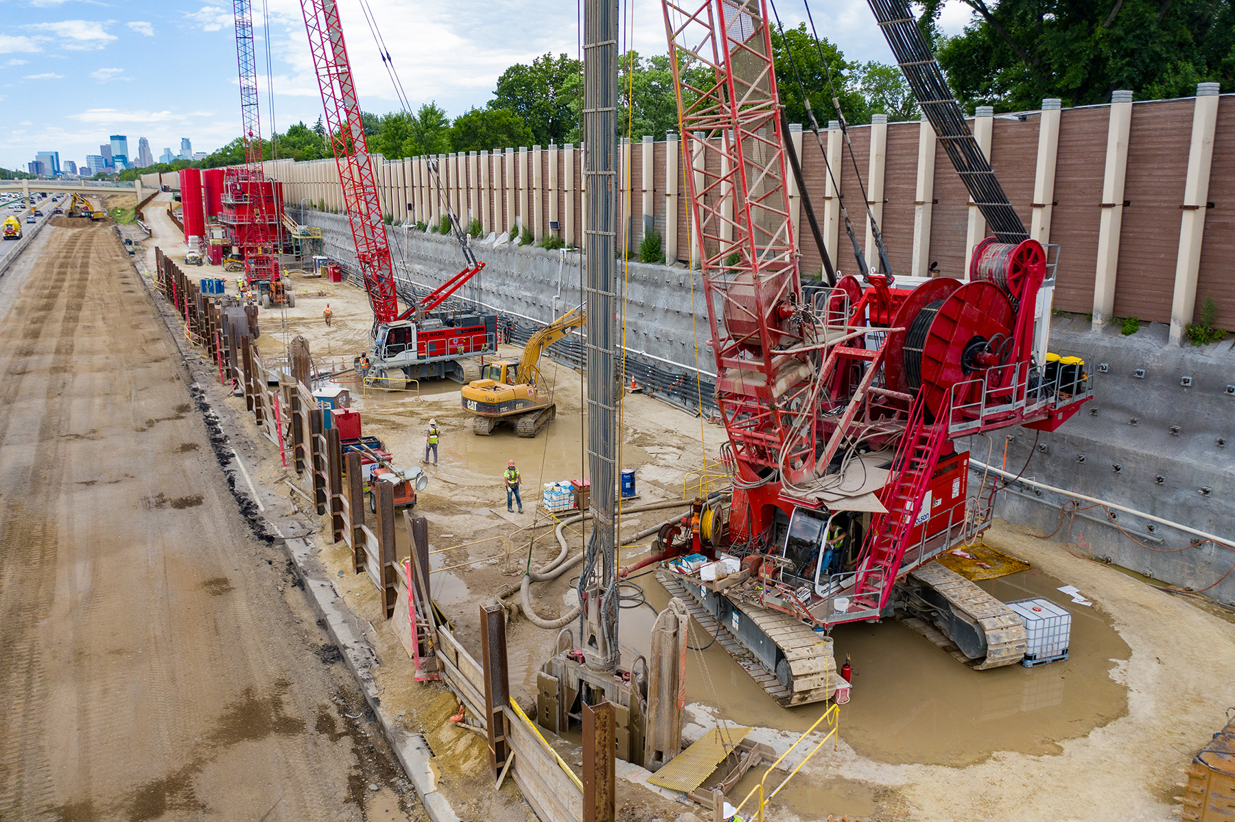 The photo shows the constricted jobsite as well as the construction of a soil nail wall in front of a noise barrier wall. 