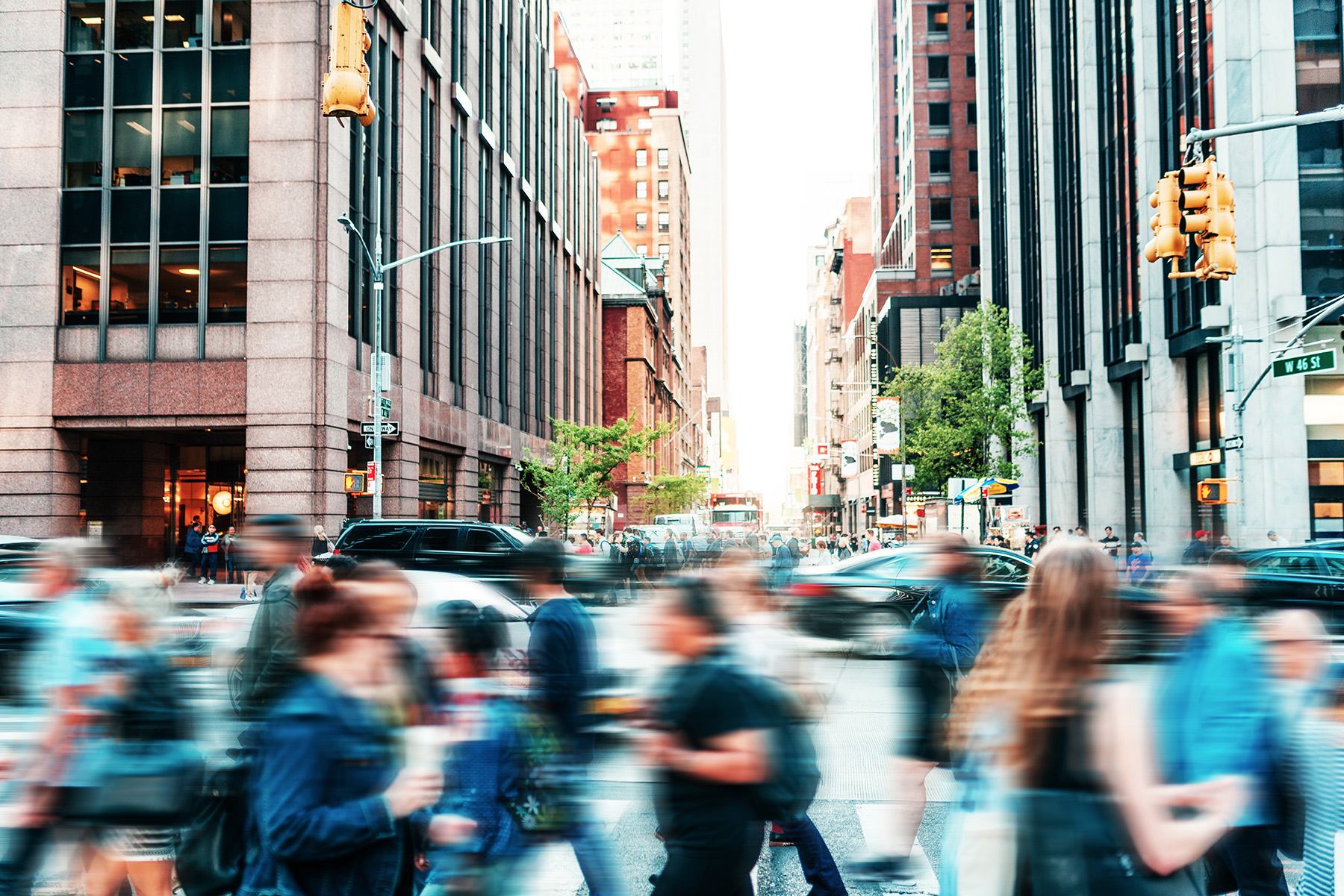 The photo shows a blur of pedestrians moving along an urban sidewalk. 