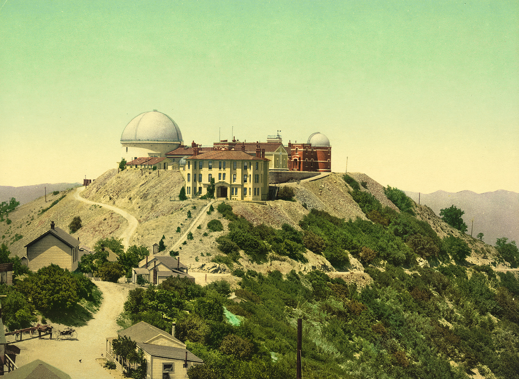 Image shows a rooftop facility consisting of a multistory building, two domed structures, and housing. A road leads to the top of the mountain. 