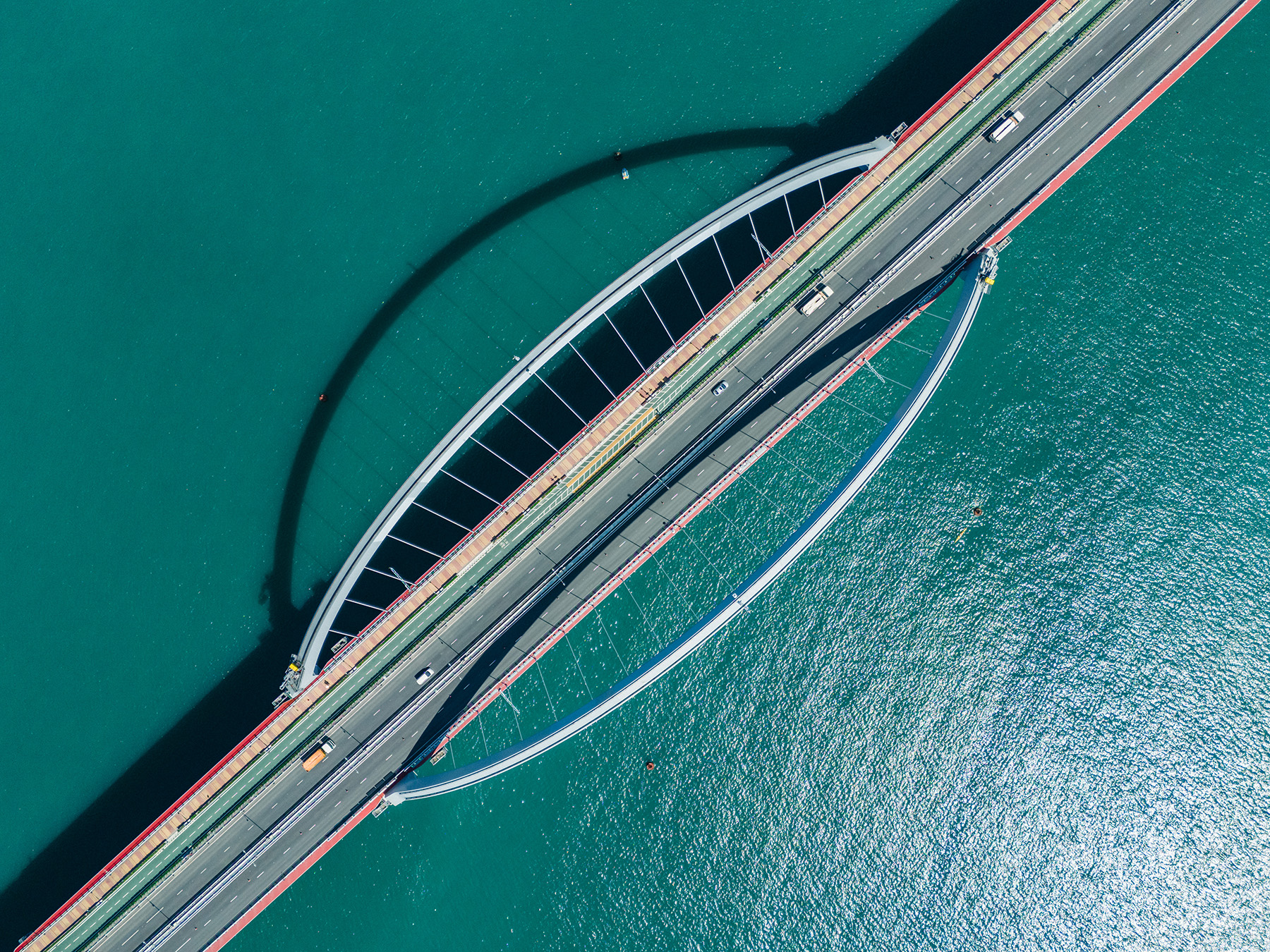 A bird’s-eye view of a two-lane bridge that has one large-spanning arch on each side. 