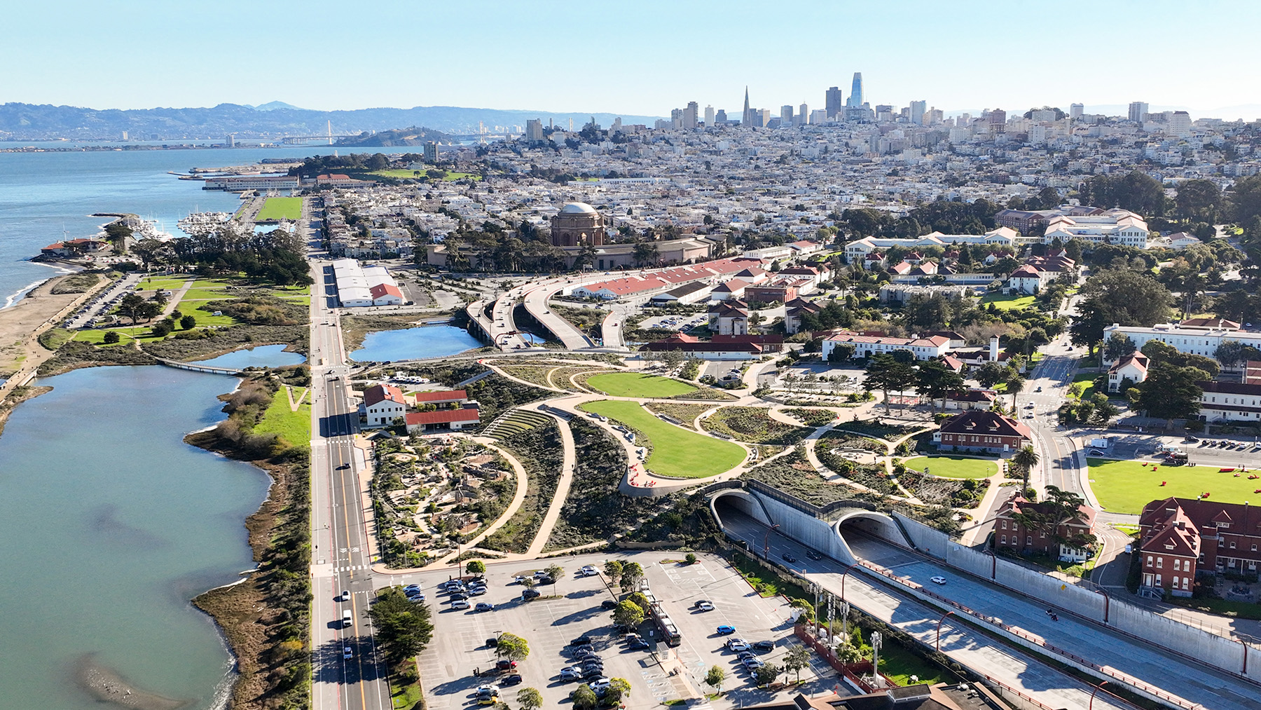 Large grass fields intermingle with walking paths, play areas, and gardens. Two tunnels sit underneath the fields