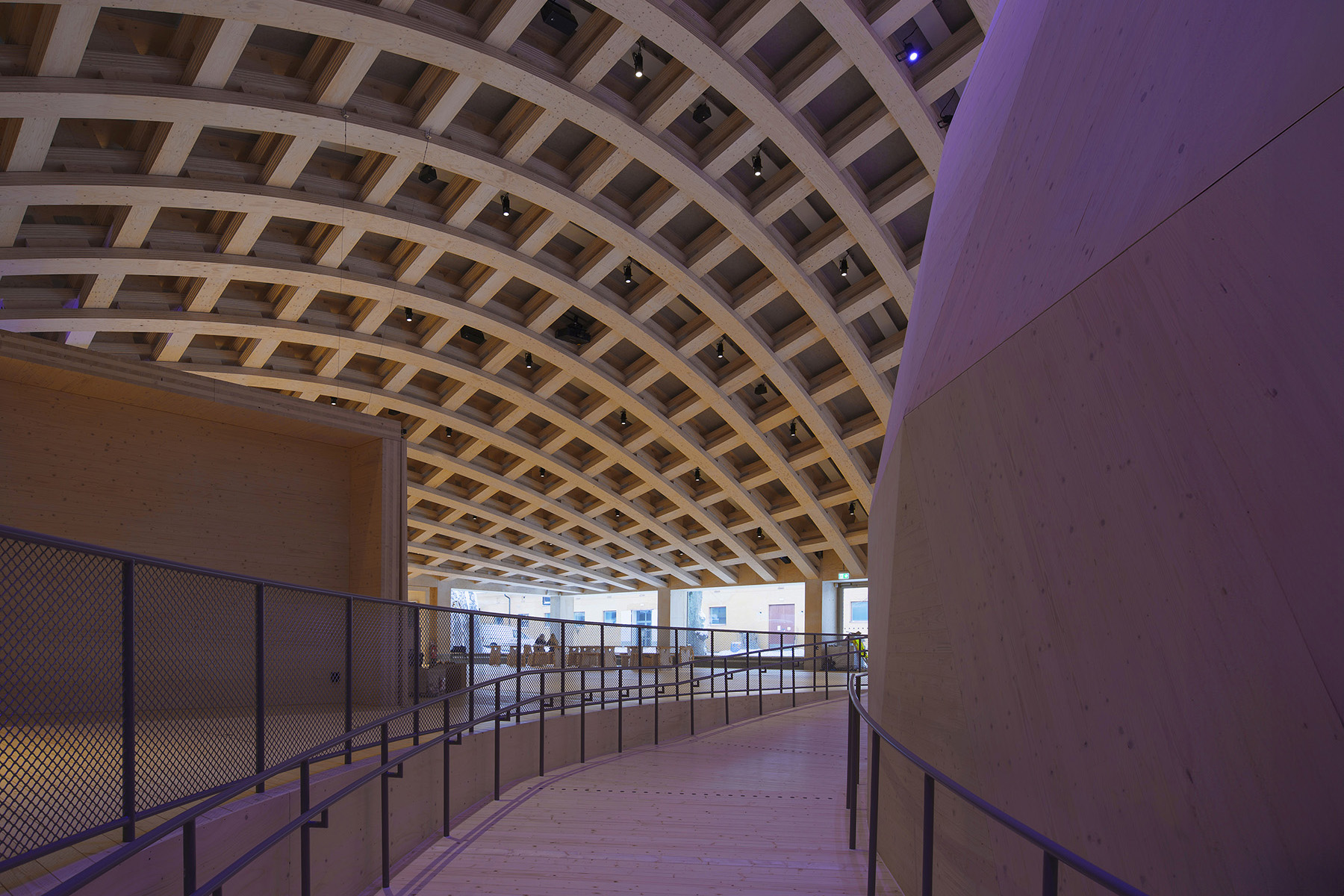 The interior of the Wisdome Stockholm depicts the crisscrossing roof beams and the edge of the domed arena. 