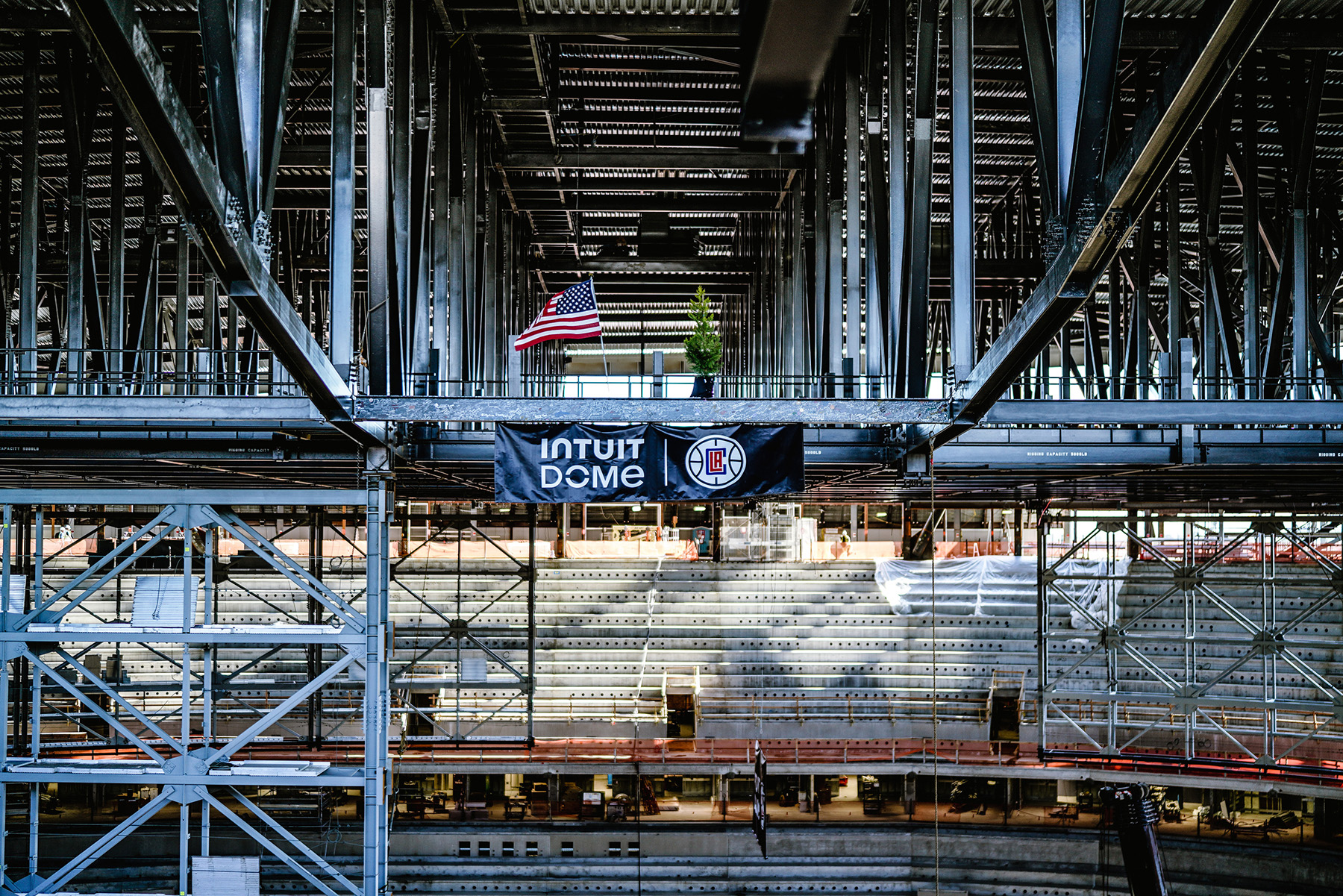 Photograph shows a stadium under construction. The steel framework and seating can be seen. 