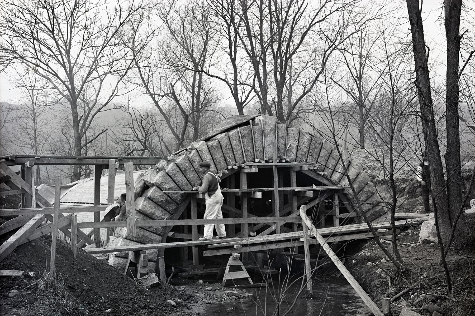 A worker constructs an arch on a bridge. 