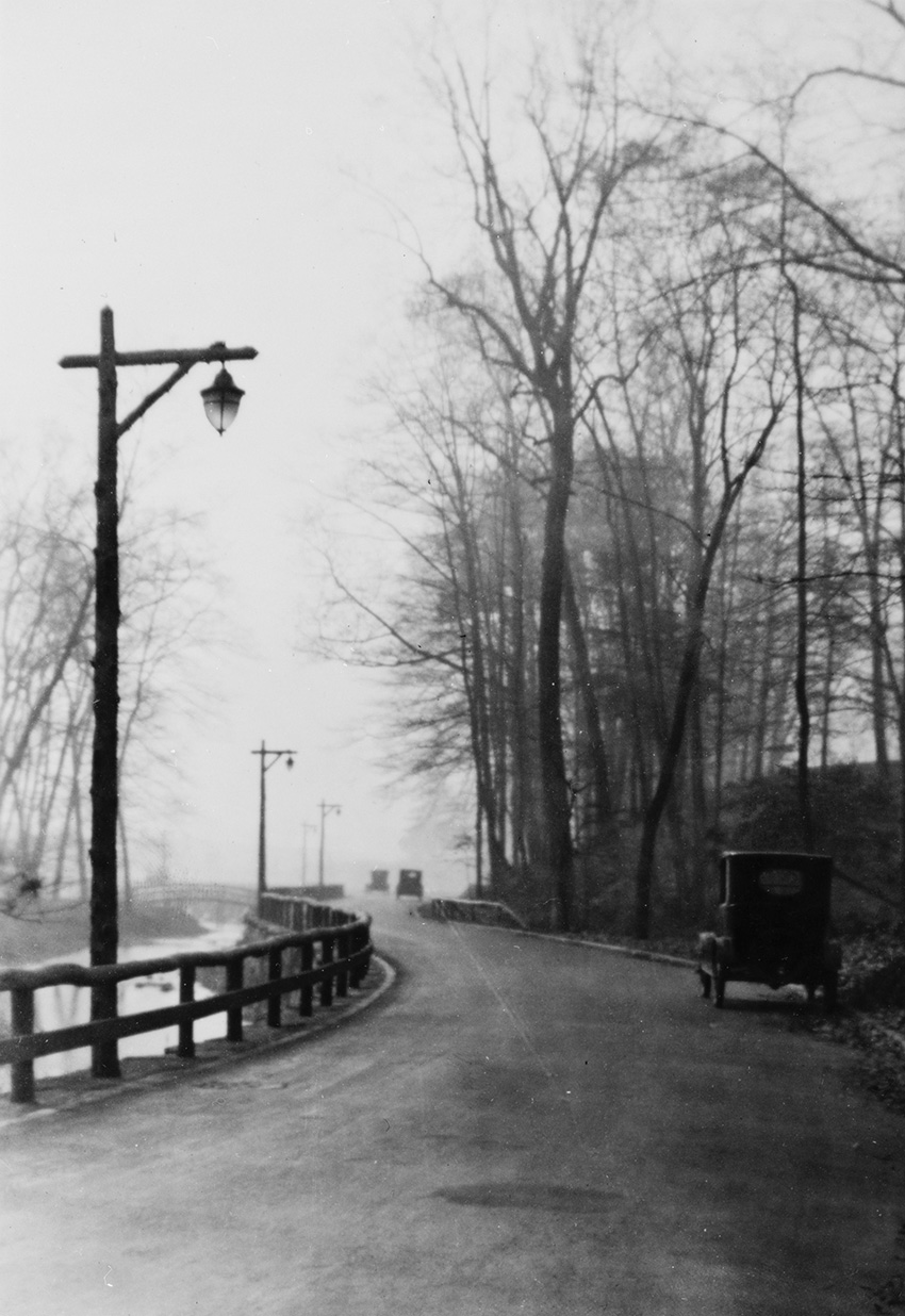 Lone cars traverse a winding parkway path. 