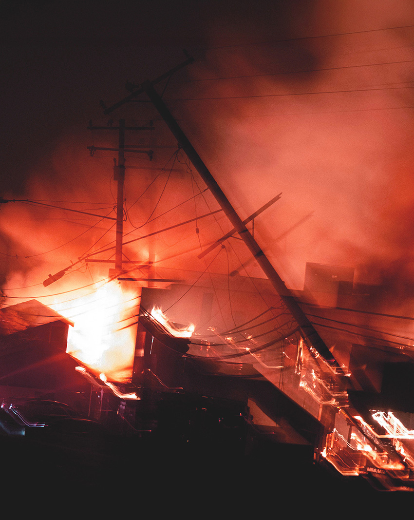 Utility poles are shown collapsing into flames.