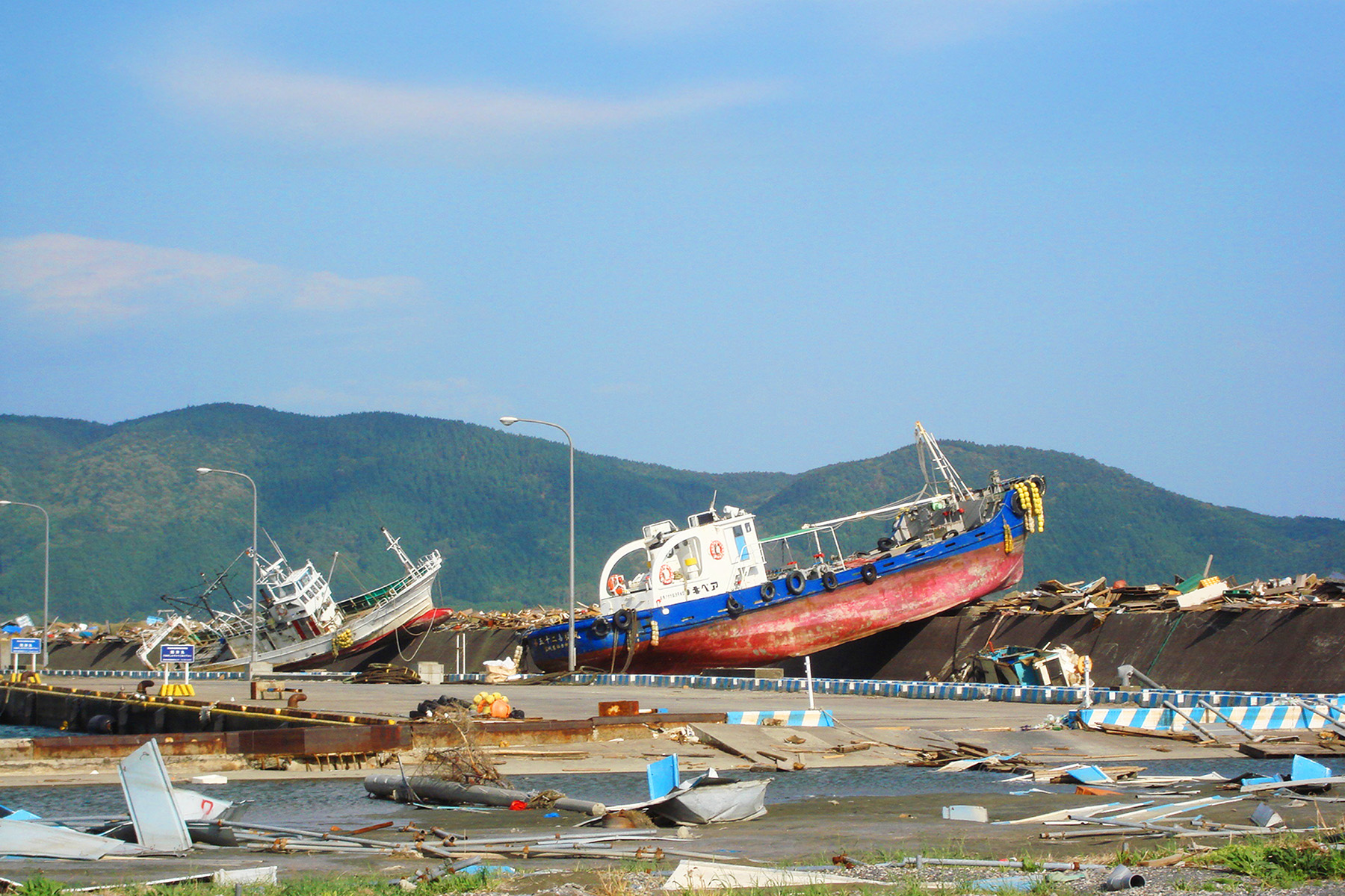 A tsunami caused a ferry to land on a pier. The pier is strewn with other debris as well.
