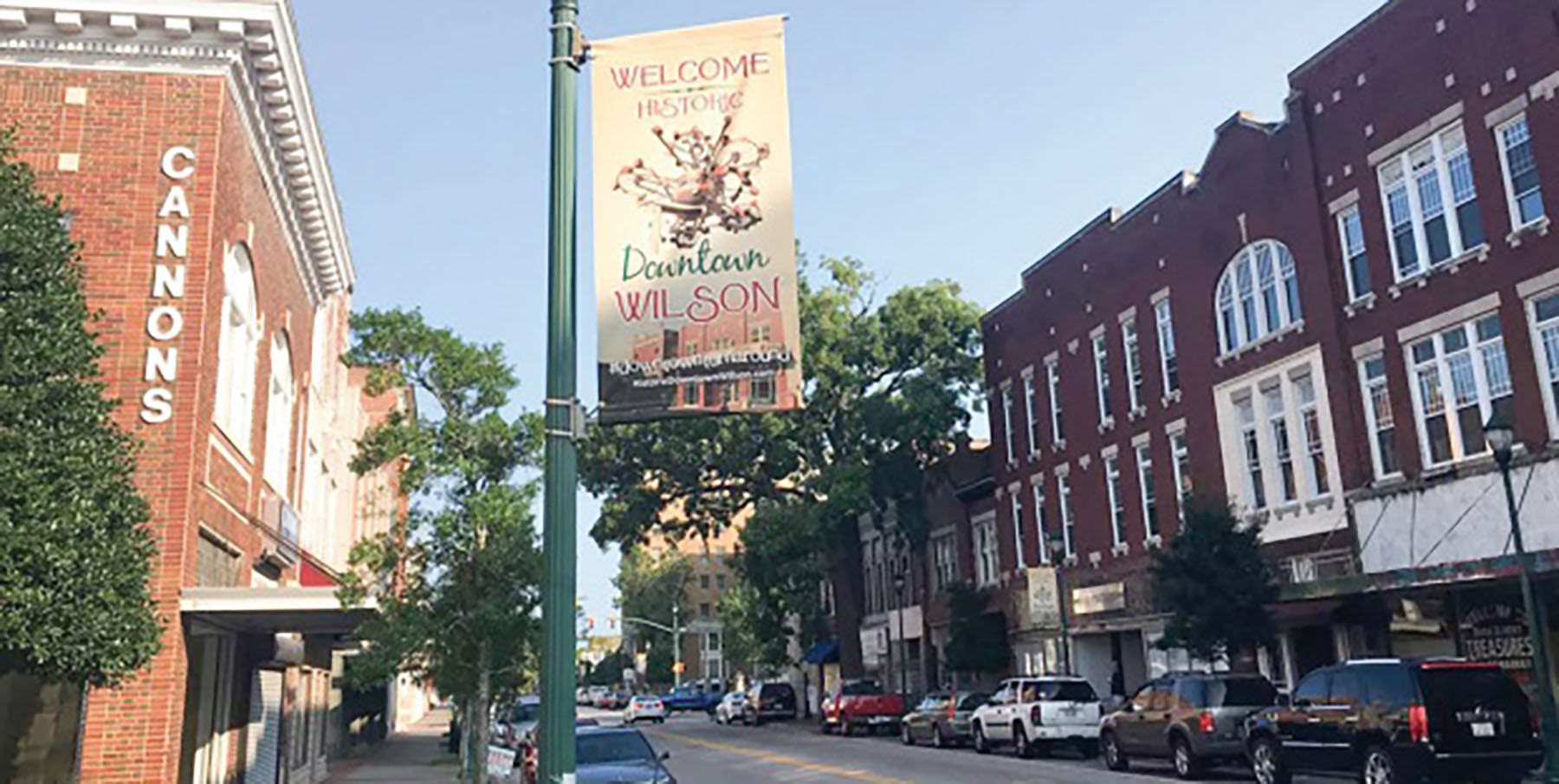 city center with cars, a welcome sign, and buildings