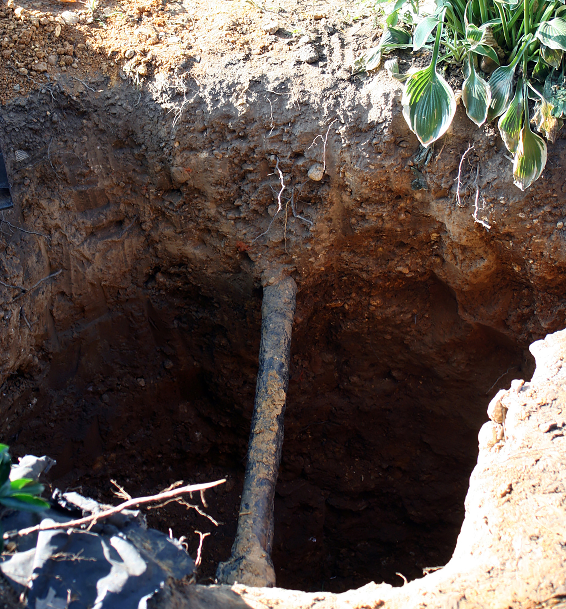 a lead pipe exposed by hole in the ground