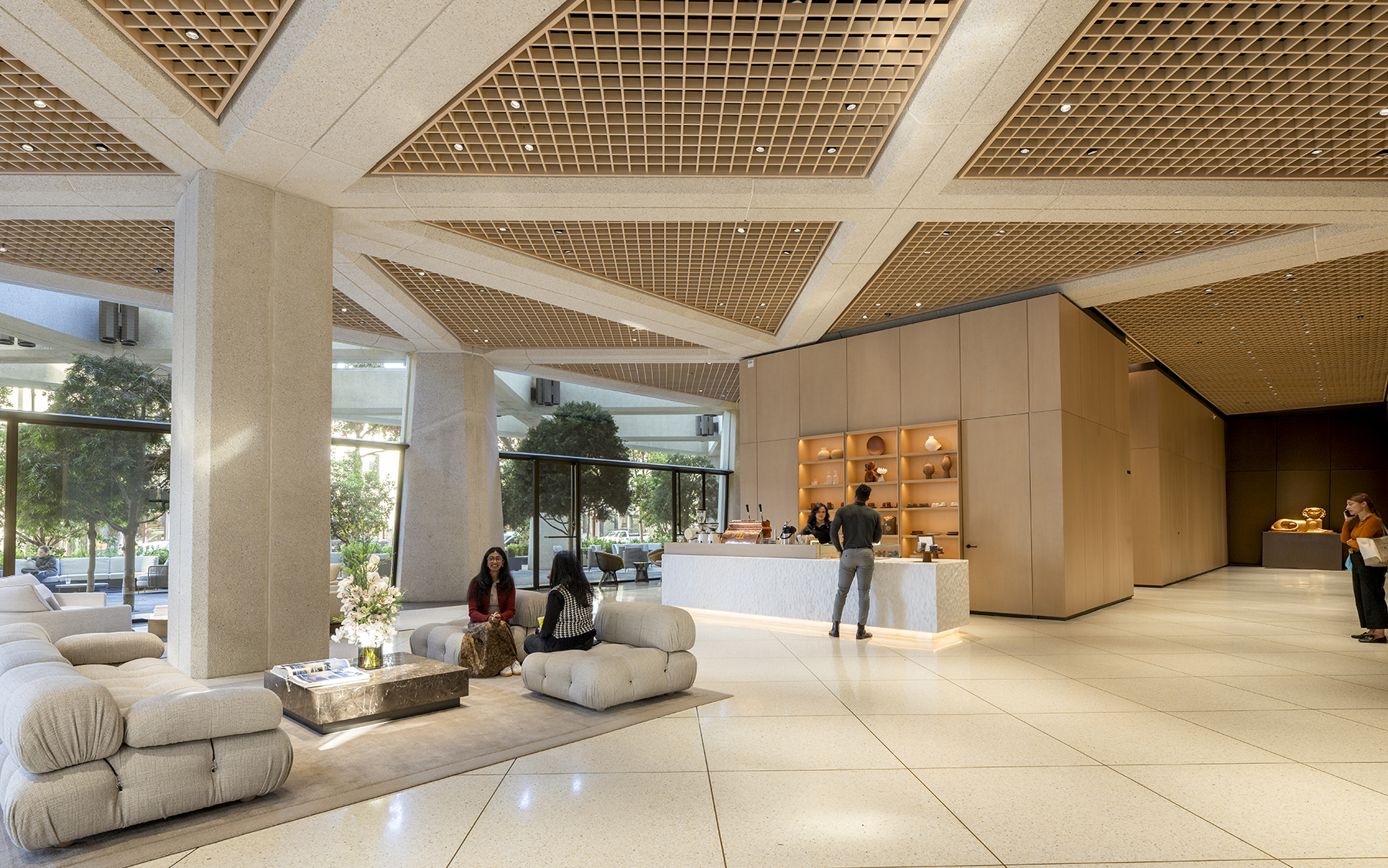 interior of building shows a sitting area with patterned ceiling, couches, and trees