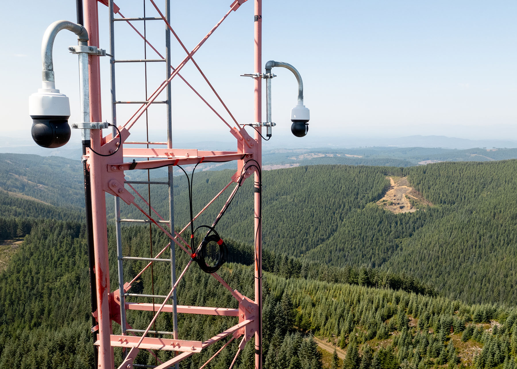 cameras are mounted on a metal structure high above a forested area