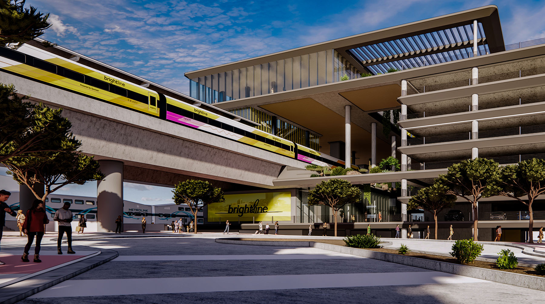 a train enters an elevated station with people on the sidewalk below