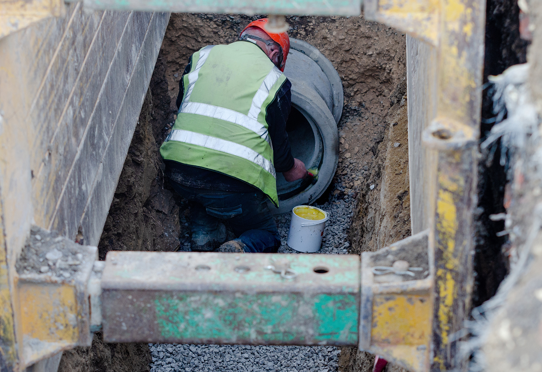 worker installs concrete pipe below ground