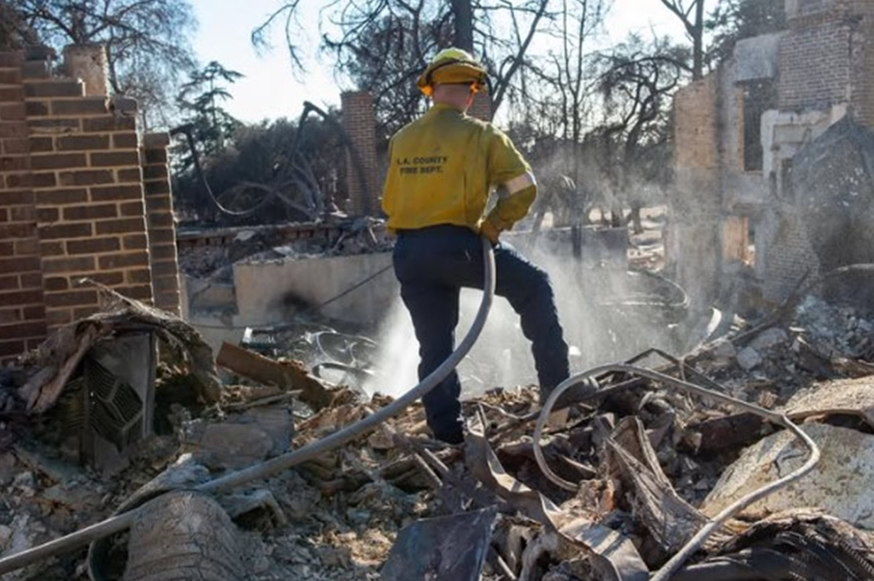 firefighter battles fire with hose