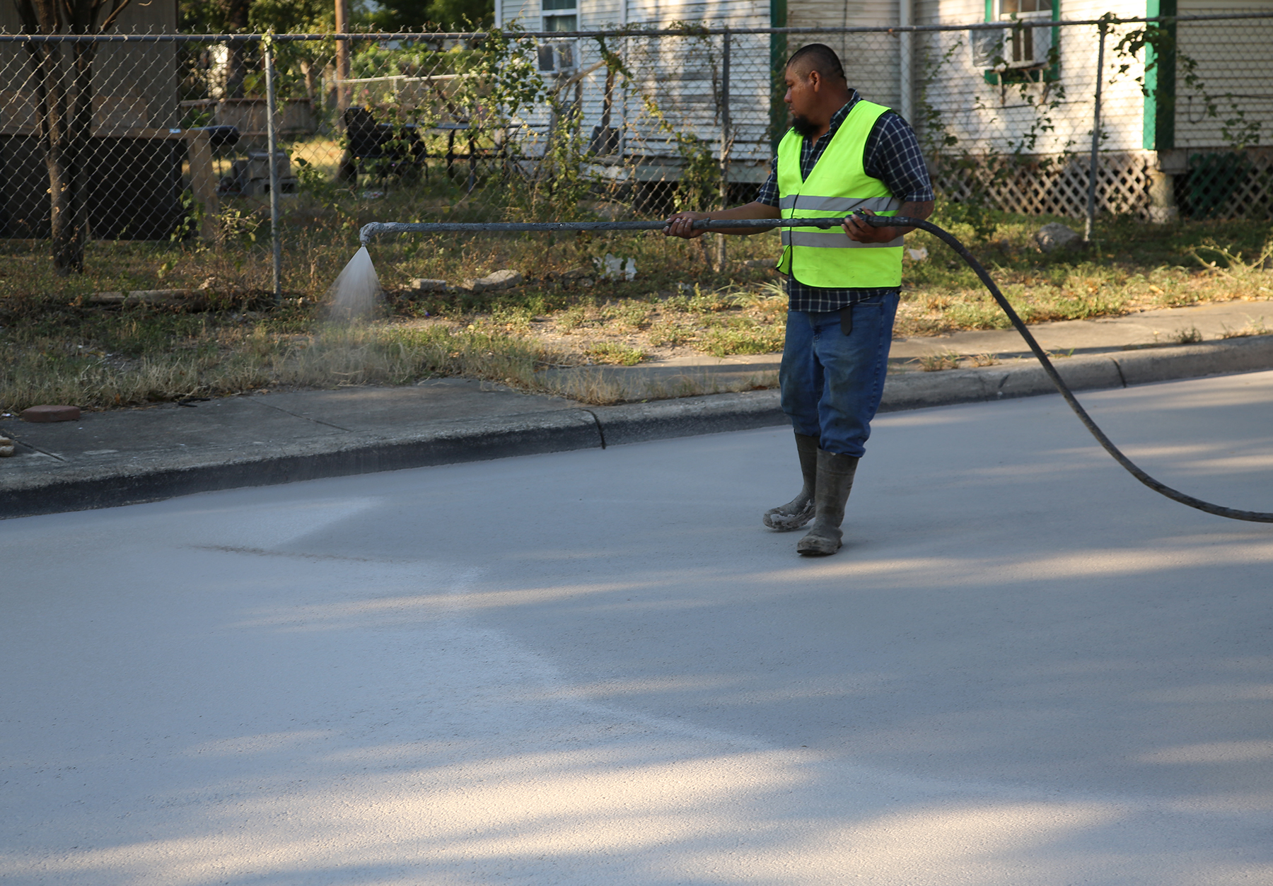 a man sprays material on the ground below with a hose