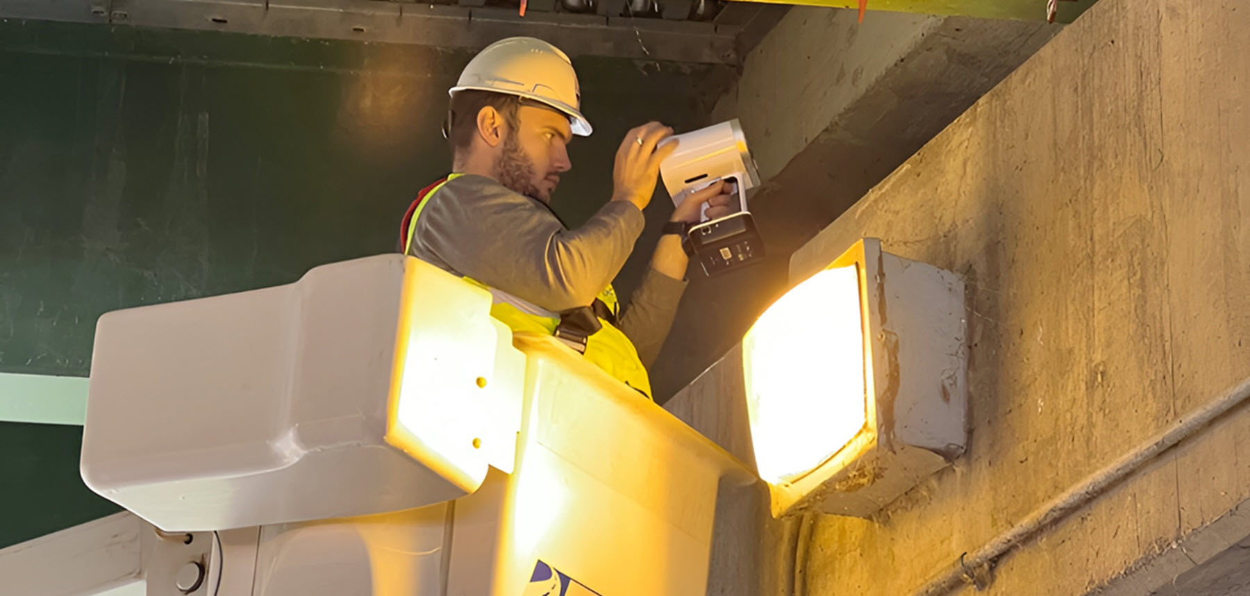 man in work bucket with hardhat uses a scanner