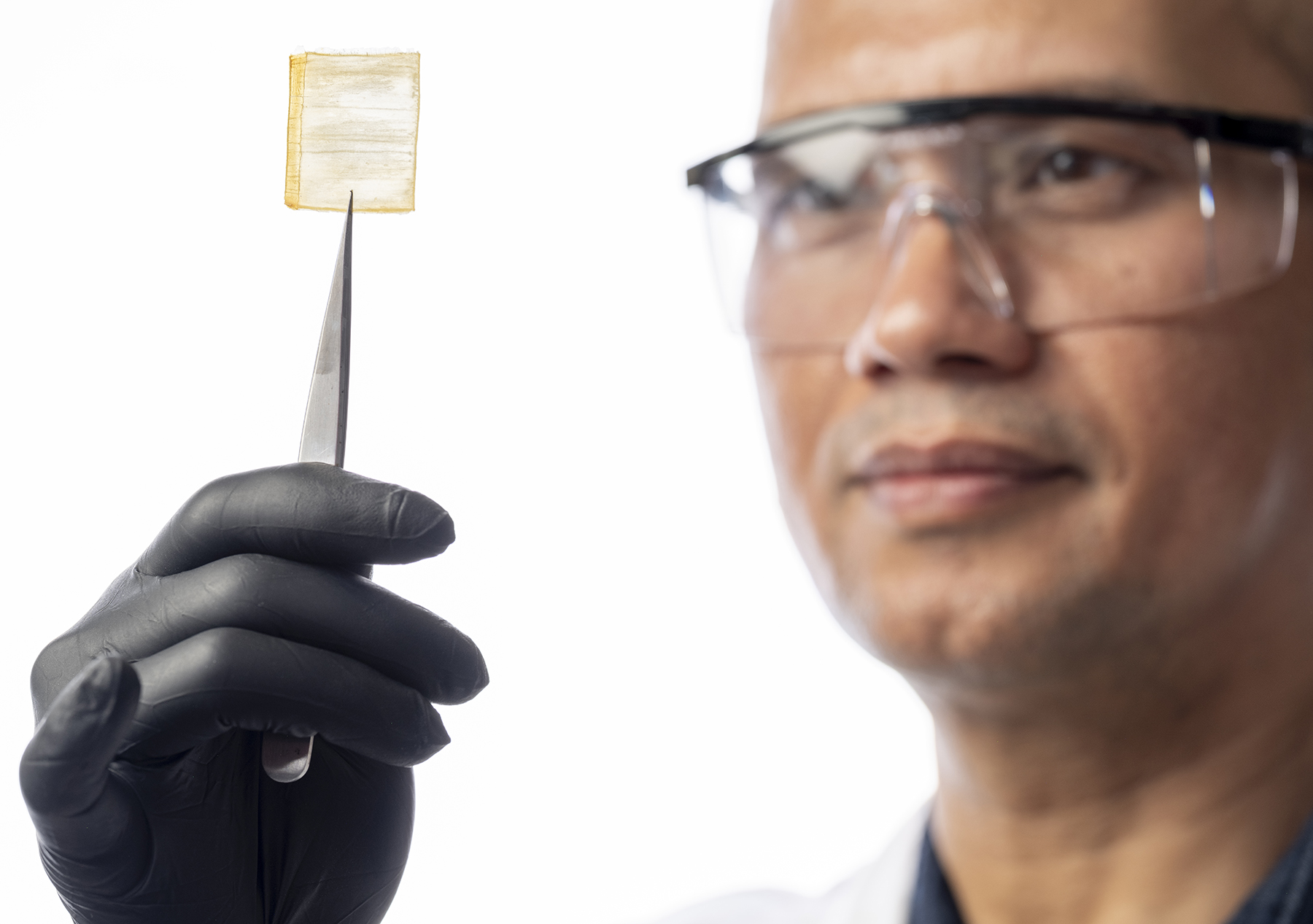 man with goggles holds up a square-shaped piece of wood with a sharp instrument man with goggles holds up a square-shaped piece of wood with a sharp instrument